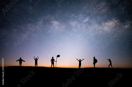 Silhouette group of tourists and looking view of star and milky way on the top of the mountain and raise their hands pointing to the stars before sunrise. We are happy to be with herself and nature.
