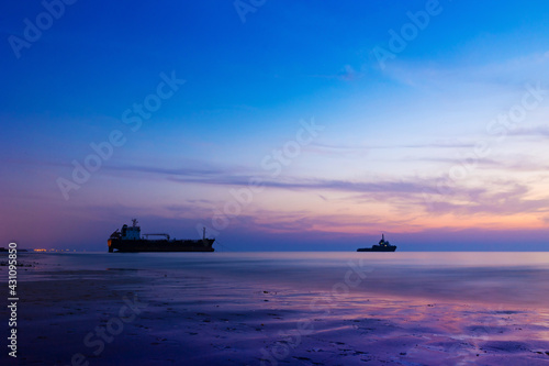 Ship Wreck along the Umm Al Quwain Coast in UAE. A stranded oil tanker vessel on the beach being rescued by another ship. Long exposure shot.