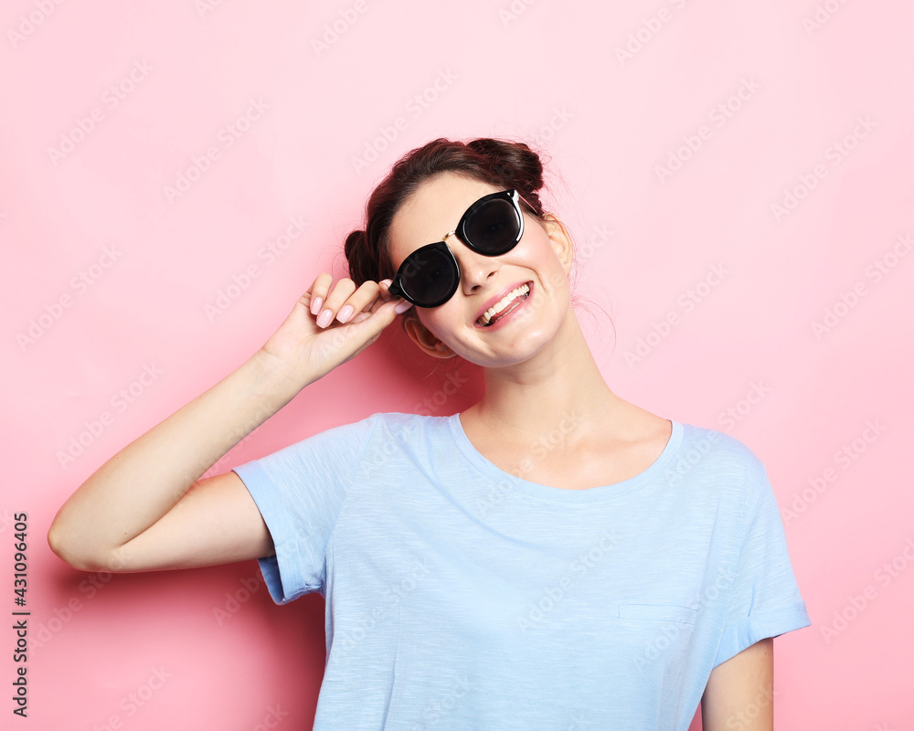 Happy time. Young cute smiling brunette woman wearing casual blue shirt and sunglasses posing over pink background. Happy time. Young cute smiling brunette woman wearing casual blue shirt and sunglasses posing over pink background.