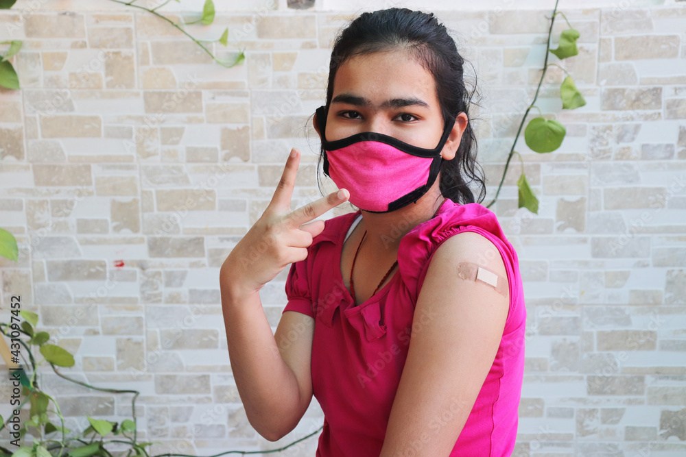Indian girl wearing mask do victory Sign after getting vaccination during new strain of covid-19