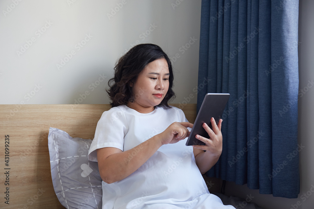 Young Asian Pregnant Woman using digital tablet to search for information Young Asian Pregnant Woman using digital tablet to search for information