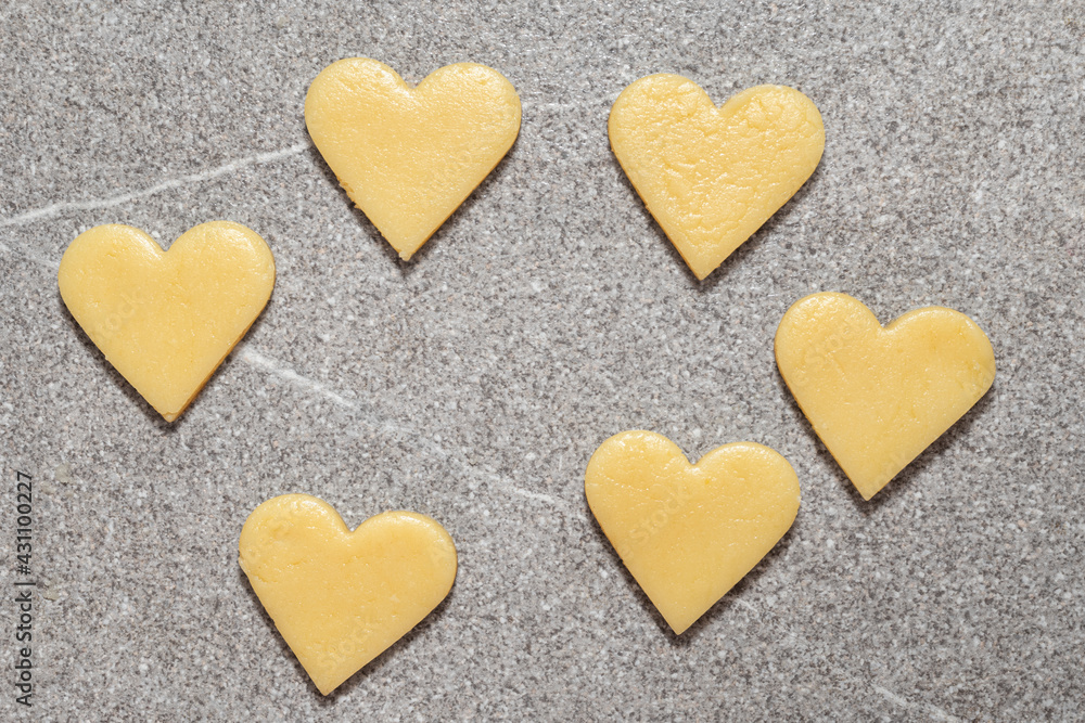 Heart cut cookies from dough on a gray table background. Raw biscuits prepared for baking homemade biscuits Heart cut cookies from dough on a gray table background. Raw biscuits prepared for baking homemade biscuits