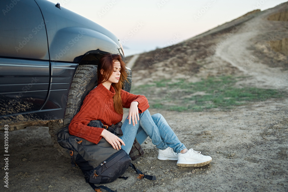 woman tourist in the mountains on nature sits near the car and mountains road landscape woman tourist in the mountains on nature sits near the car and mountains road landscape