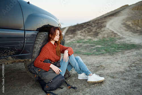 woman tourist in the mountains on nature sits near the car and mountains road landscape © SHOTPRIME STUDIO