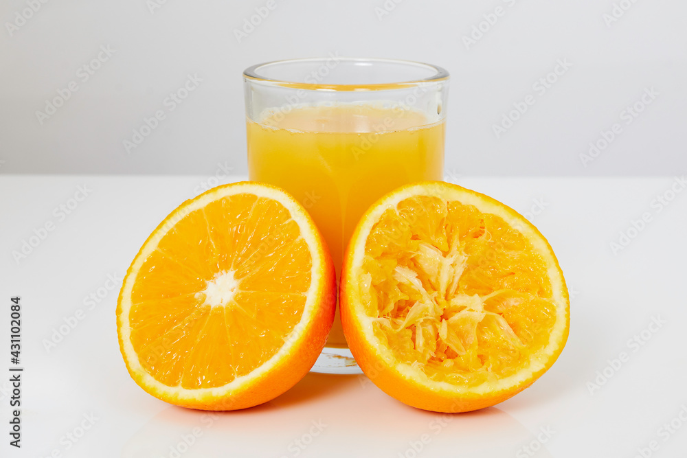 Glass with orange juice, one half of orange with juice and the other half of squeezed orange Glass with orange juice, one half of orange with juice and the other half of squeezed orange