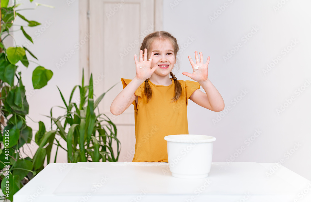 A kid grimy funny girl shows hands smeared in flour. children's culinary hobby. Simple and delicious recipe. Culinary school. A kid grimy funny girl shows hands smeared in flour. children's culinary hobby. Simple and delicious recipe. Culinary school.