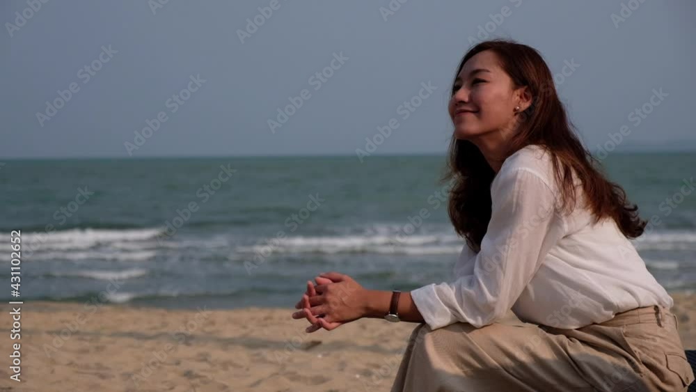 Slow motion of a beautiful young asian woman sitting on the beach Slow motion of a beautiful young asian woman sitting on the beach