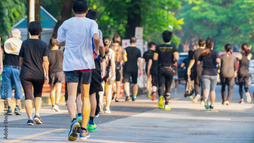view of back of people run and walk at pedestrian garden park. group of ...