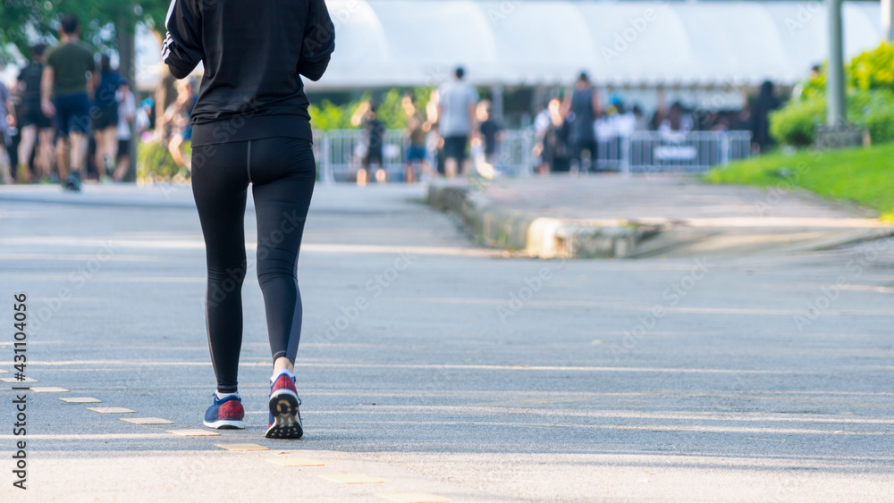 view of back of people run and walk at pedestrian garden park. group of ...