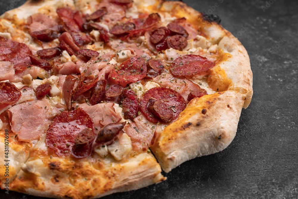 Four meat pizza on a dark concrete background