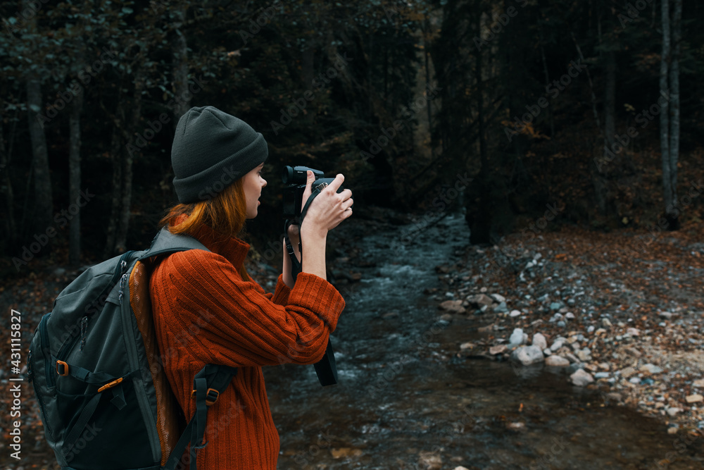 woman with a camera near a pond in the mountains on nature and trees forest landscape woman with a camera near a pond in the mountains on nature and trees forest landscape