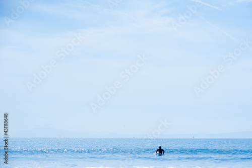 水平線が見える海原で波を待つサーファー 