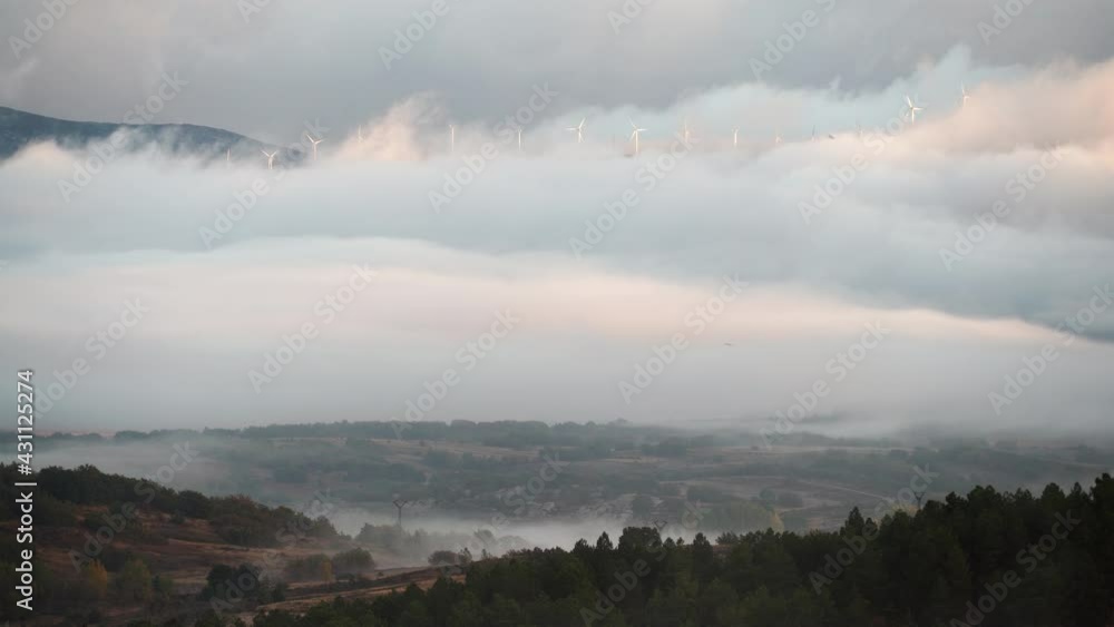 Morning view. Fog over valley and wind turbines farm on hill covered with clouds. Aguilar de Campoo in province of Palencia, Castile and Leon community, northern Spain. Morning view. Fog over valley and wind turbines farm on hill covered with clouds. Aguilar de Campoo in province of Palencia, Castile and Leon community, northern Spain.