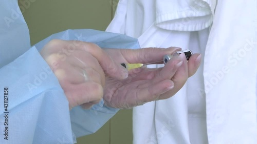 Vaccination against COVID-19, nurse in transparent protective gloves preparing vaccine for injection on vaccinal point for massive immunisation.