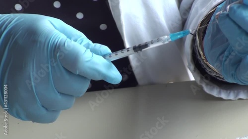 Vaccination against COVID-19, nurse in blue gloves preparing vaccine for injection on vaccinal point for massive immunisation