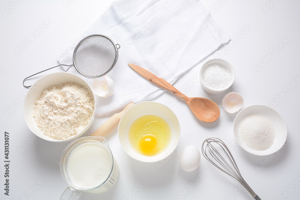 Frame of food ingredients for baking on a white background. Flour, eggs, sugar and milk in white and wooden bowls . Cooking and baking concept. Frame of food ingredients for baking on a white background. Flour, eggs, sugar and milk in white and wooden bowls . Cooking and baking concept.