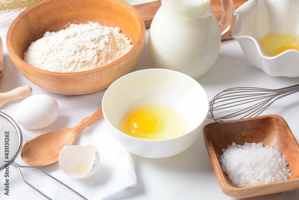 Frame of food ingredients for baking on a white background. Flour, eggs, sugar and milk in white and wooden bowls . Cooking and baking concept. Frame of food ingredients for baking on a white background. Flour, eggs, sugar and milk in white and wooden bowls . Cooking and baking concept.