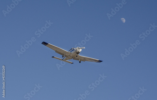 Ein Kleinflugzeug am Himmel. Der Mond im Hintergrund