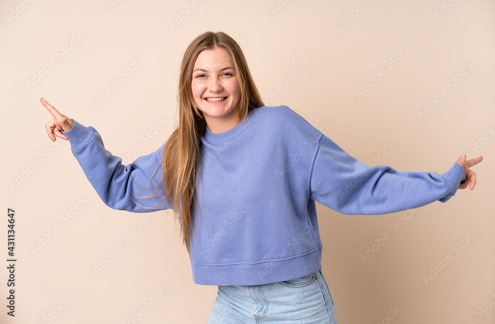 Teenager Ukrainian girl isolated on beige background pointing finger to the laterals and happy Teenager Ukrainian girl isolated on beige background pointing finger to the laterals and happy