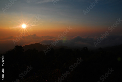 Landscape Tranquil scene of the sunrise with Orange sky and fog around the mountain in the morning at doi pha hom pok national park Thailand.