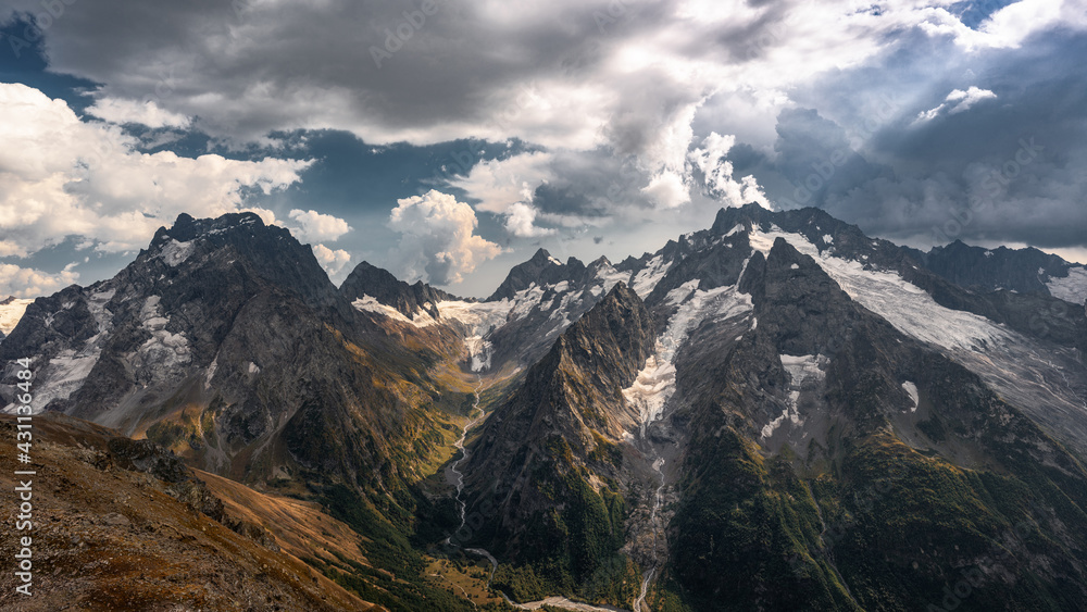 Epic landscape. A magnificent panorama of the Caucasus Mountains with sunlight in high resolution. Desktop wallpaper.