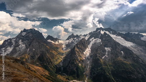 Epic landscape. A magnificent panorama of the Caucasus Mountains with sunlight in high resolution. Desktop wallpaper. © Aleksei
