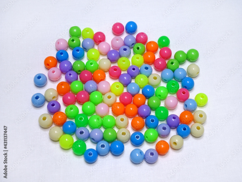 Photo of scattered round acrylic colored beads on a light cotton background