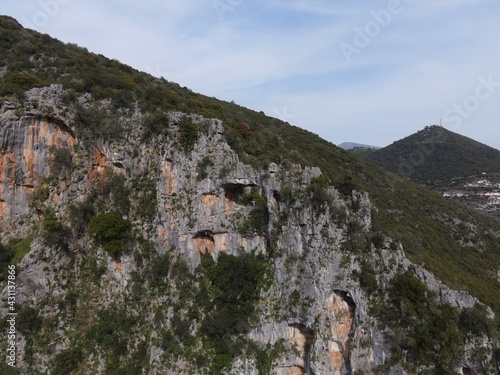 Aerial drone view dragon hole of St. George in the mountain ridge next to the river louros and the roman aqueduct of ancient nikopolis in preveza, epirus, greece. photo