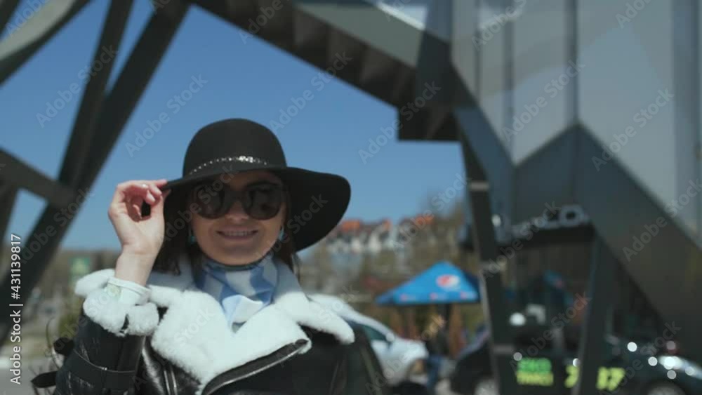 Happy smiling European woman spinning outdoors under urban bridge. Happiness, relax concept.Cool girl in a hat and black glasses. Happy smiling European woman spinning outdoors under urban bridge. Happiness, relax concept.Cool girl in a hat and black glasses.