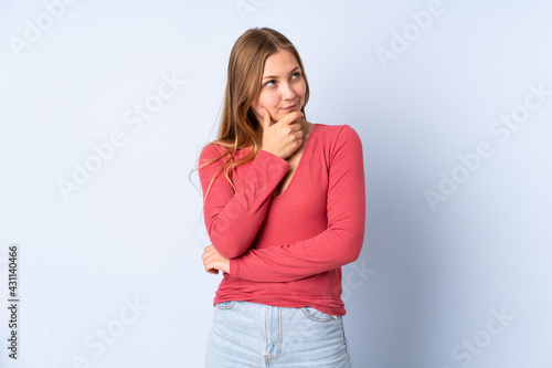 Teenager Ukrainian girl isolated on blue background thinking an idea while looking up