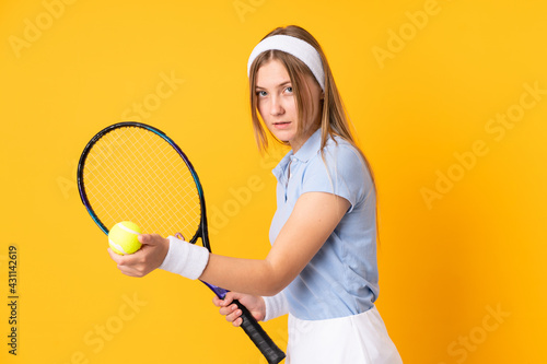 Teenager Ukrainian girl tennis player isolated on yellow background playing tennis © luismolinero