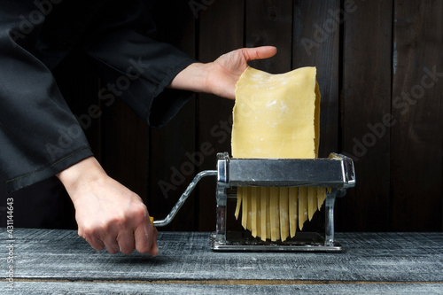 Cooking homemade pasta with a pasta machine on a dark wood