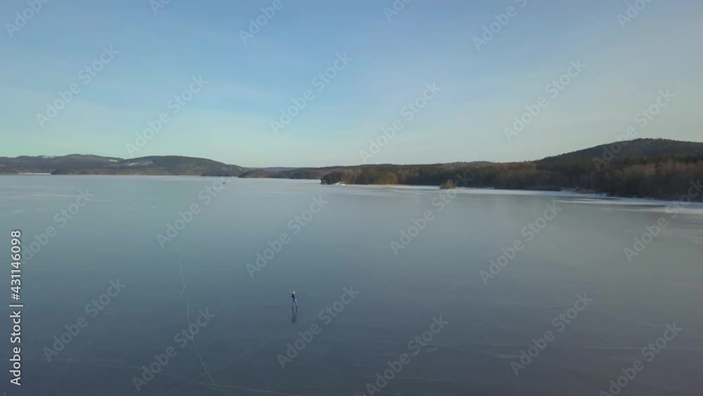 A person in solitude ice-skating on a big lake A person in solitude ice-skating on a big lake