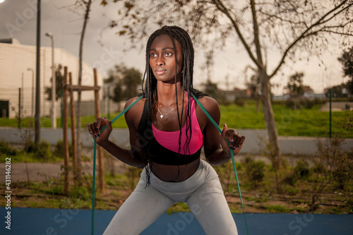 front view of a black woman doing squats on street. fitness routine