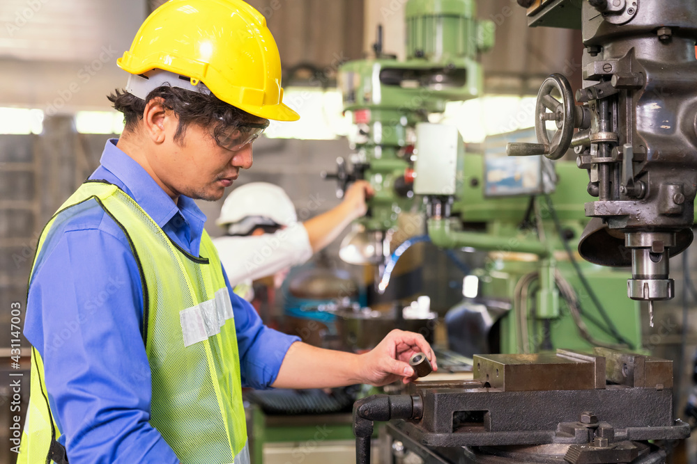 Asian mechanical engineer operating industrial lathe machine. Mechanical technician operative of machine in factory. Asian mechanical engineer operating industrial lathe machine. Mechanical technician operative of machine in factory.