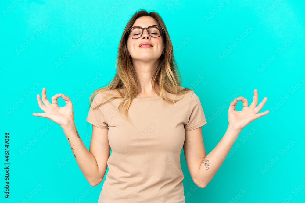 Fototapeta premium Young caucasian woman isolated on blue background in zen pose