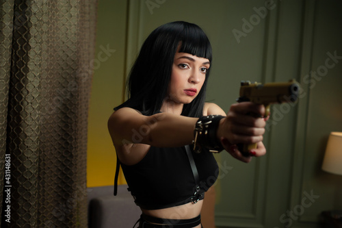 a female hitman in a hotel aims a gun at a victim with a scared face