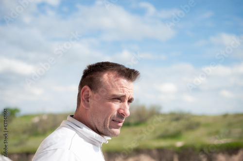 An attractive adult Caucasian man looking at the horizon from a balcony with an unfocused background of sky and mountains