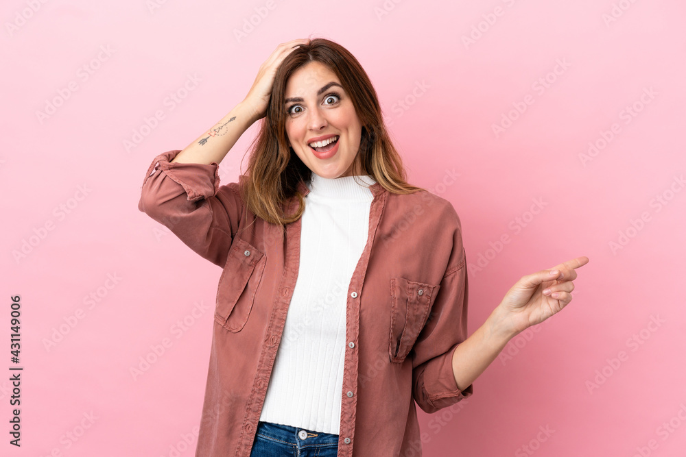 Caucasian woman isolated on pink background surprised and pointing finger to the side Caucasian woman isolated on pink background surprised and pointing finger to the side