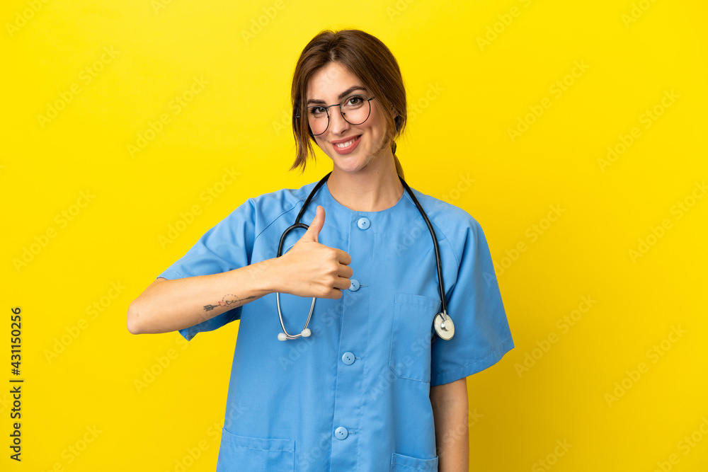Surgeon doctor woman isolated on yellow background giving a thumbs up gesture Surgeon doctor woman isolated on yellow background giving a thumbs up gesture