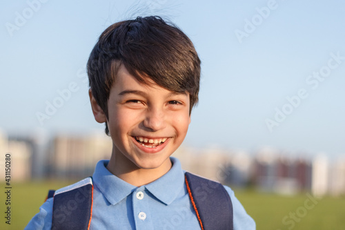 Returning to school concept, portrait of happy boy with backpack, school child waiting for school bus, primary school student, on the way to school