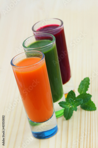Obraz na płótnie Carrot, spinach and beetroot smooties in transparent tall glasses on wooden surface
w salonie