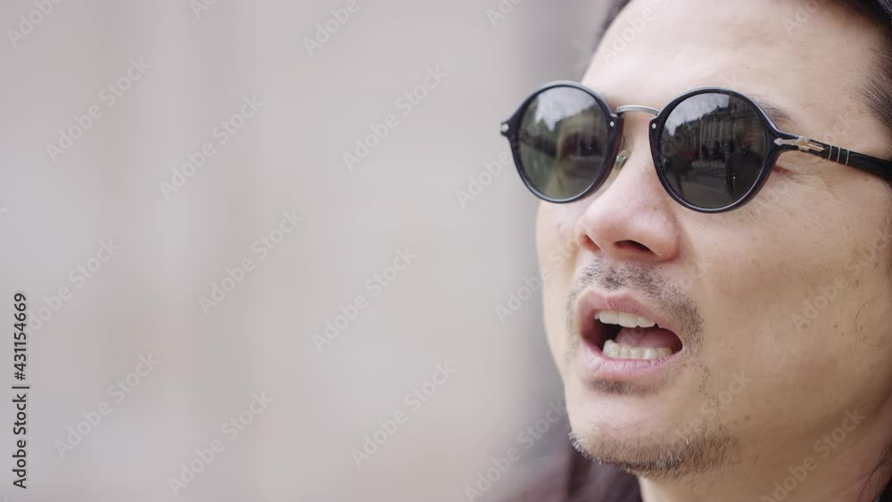 Asian man in glasses talking during a street interview Asian man in glasses talking during a street interview