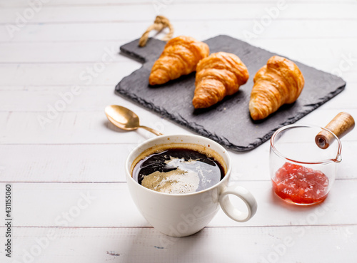 Coffee white cup, croissants on white wooden table background, selective focus. Breakfast concept