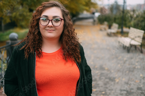 Enjoying walk. Happy plus size woman. Body positive. Healthy lifestyle. Smiling fatty lady in sportive clothes spectacles on street alley autumn season copy space. © golubovy