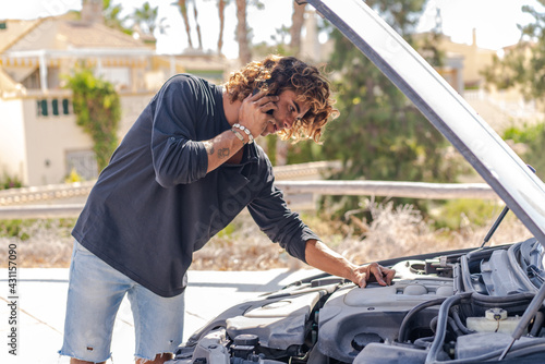 Young caucasian man trying to repair a breakdown in his car
