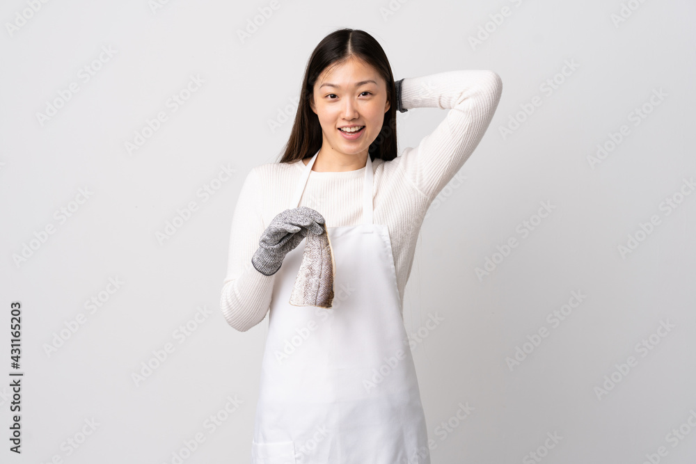 Chinese fishmonger wearing an apron and holding a raw fish over isolated white background laughing Chinese fishmonger wearing an apron and holding a raw fish over isolated white background laughing