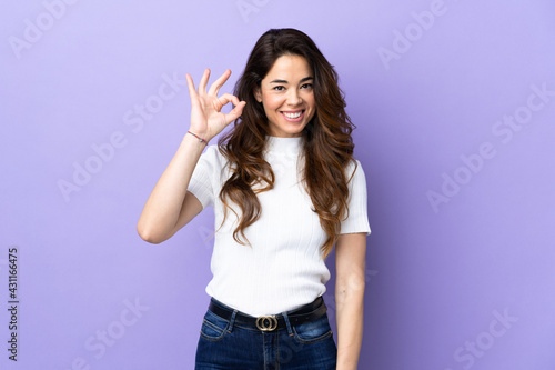 Woman over isolated purple background showing ok sign with fingers