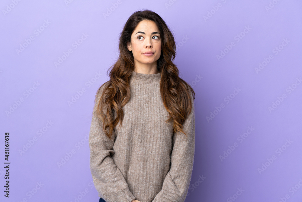 Woman over isolated purple background making doubts gesture looking side Woman over isolated purple background making doubts gesture looking side