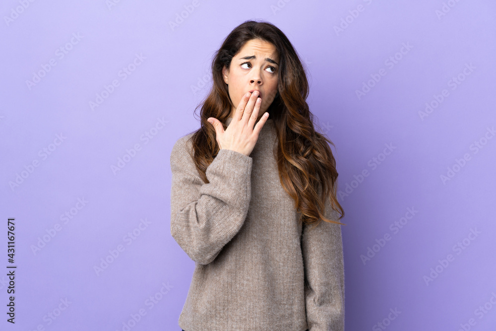 Woman over isolated purple background yawning and covering wide open mouth with hand Woman over isolated purple background yawning and covering wide open mouth with hand